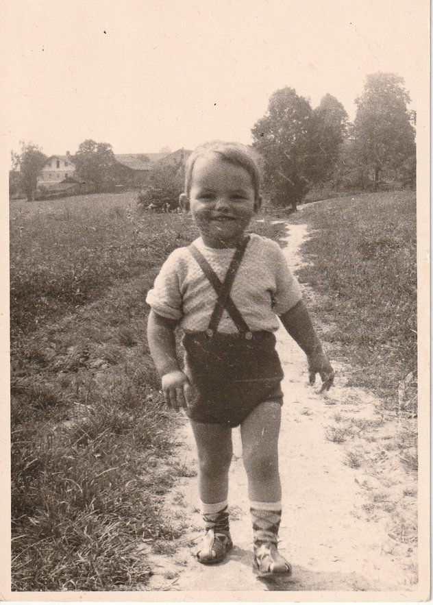 Kleiner Bub mit kurzer Hose und Hosenträger auf einem Feldweg auf Schwarz-Weiß Foto