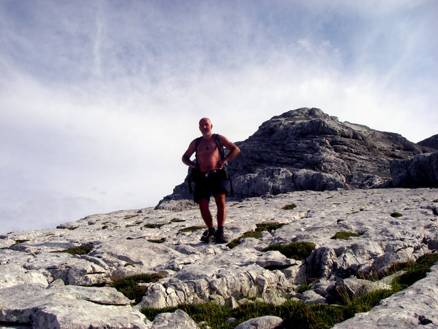 Leicht bekleideter Bergsteiger auf einer großen Karstplatte im Hochgebirge