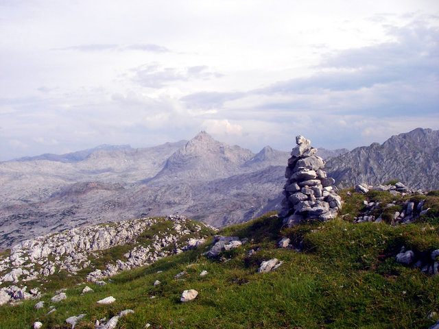 Steinmanndl auf einem einsamen Gipfel über einem weiten Karstplateau