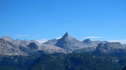 Ein markanter spitzer Berg ragt aus einem wilden Gebirge empor