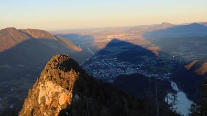 Berggipfel wirft einen pyramidialen Schatten auf eine Stadt