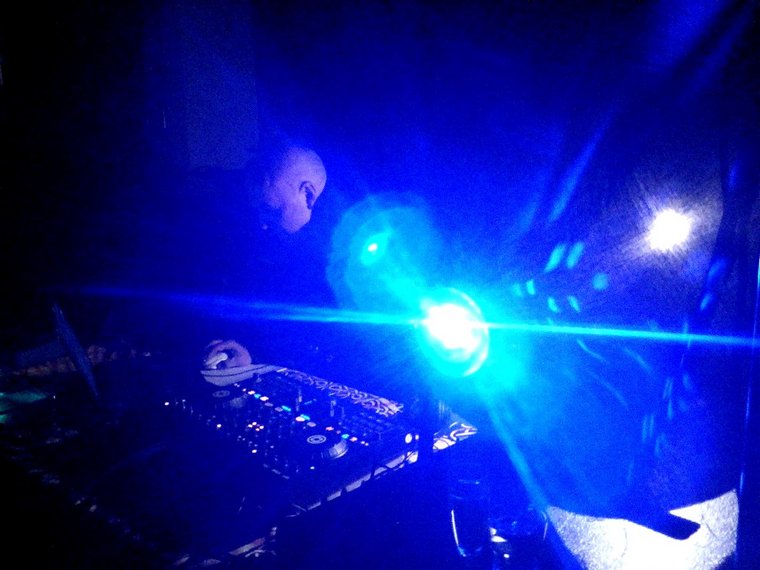 Ein DJ. bei blauem Discolicht an den Turntables