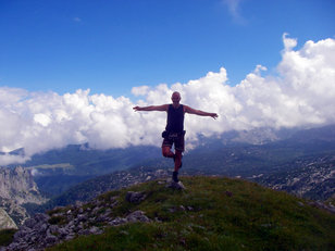 Mann auf einem Bein auf Berggipfel balancierend