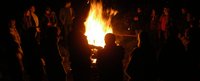 Mehrere Menschen stehen um ein großes Feuer